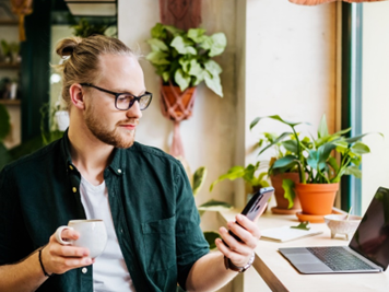 A person sitting at a table with a computer and a phone contemplating offers of funding and investment